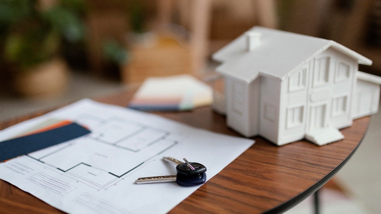 Maquete de casa, planta baixa e chaves sobre a mesa